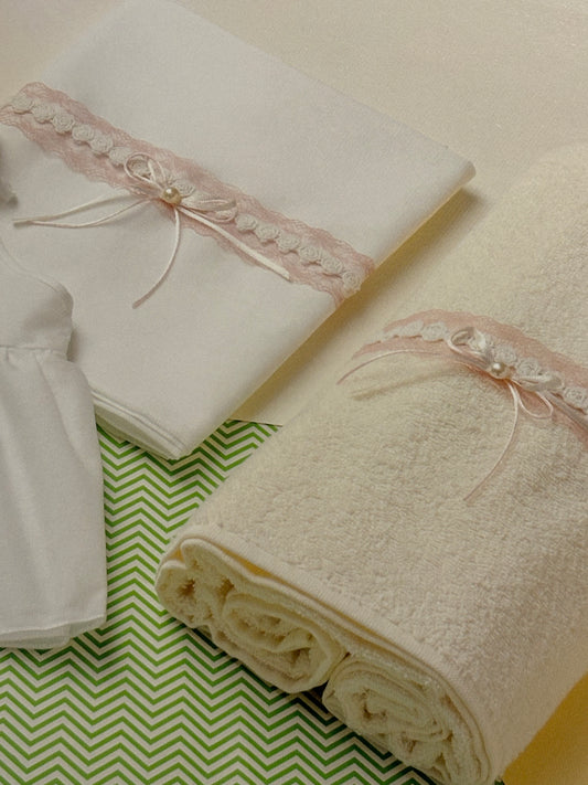 Set of white towels with lace trim on a green and white patterned surface